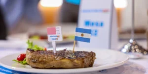 Bife de carne vacuna a la parrilla en un plato, con banderita de Argentina y cartel de Argentine Beef